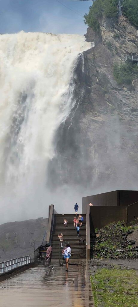 Personas a lo lejos subiendo las escaleras que conducen a la base de la Cascada de Montmorency, en Canadá