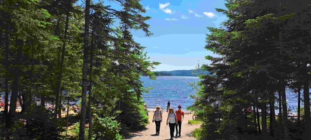 Tres personas saliendo de la zona de la Playa Édouard en el Parque La Mauricie en Canadá