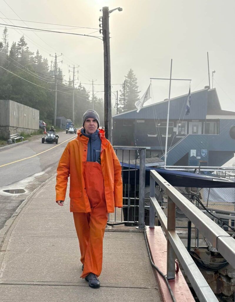 Hombre vestido con el traje color naranja de las excursiones para avistar ballenas en Tadoussac, Canadá