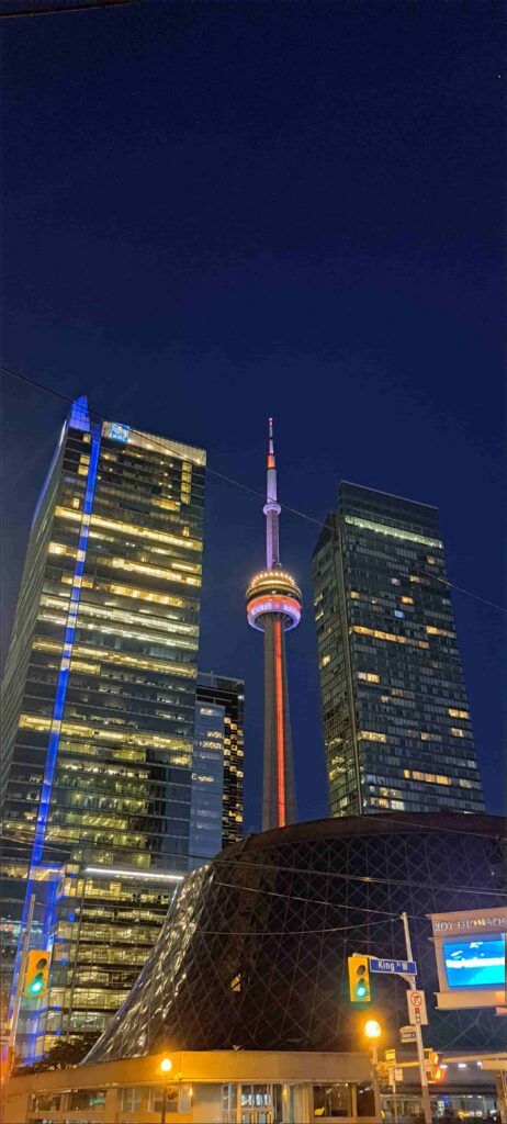 Vista de la CN Tower iluminada, entre dos rascacielos también iluminados, en Toronto, Canadá