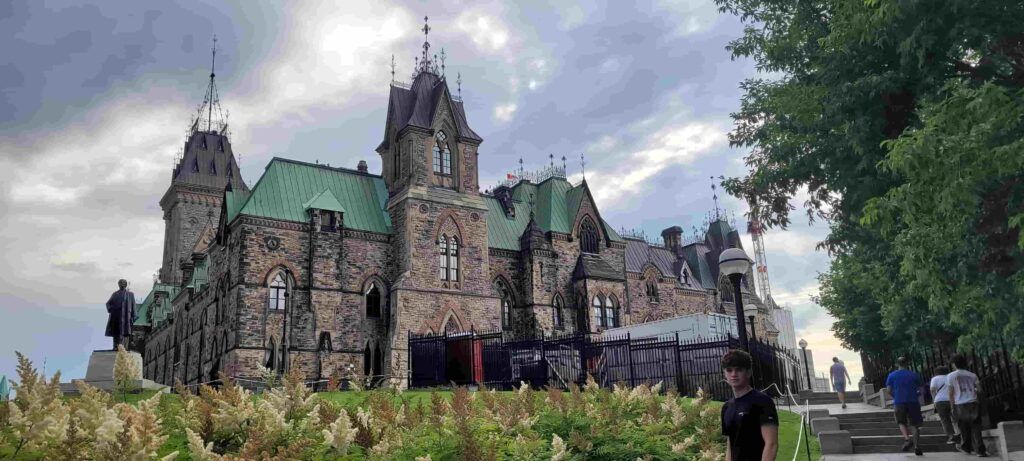 Persona posando por la parte de atrás del edificio del bloque este de la Colina del Parlamento en  Ottawa, Canadá