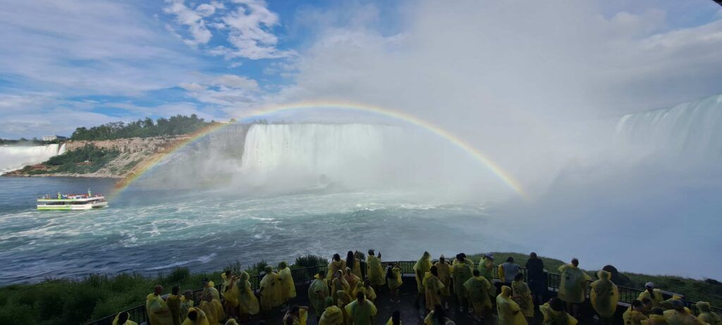 Arcoiris en las Cataratas del Niágara,  y personas con los chubasqueros amarillos de la excursión Journey Behind The Falls