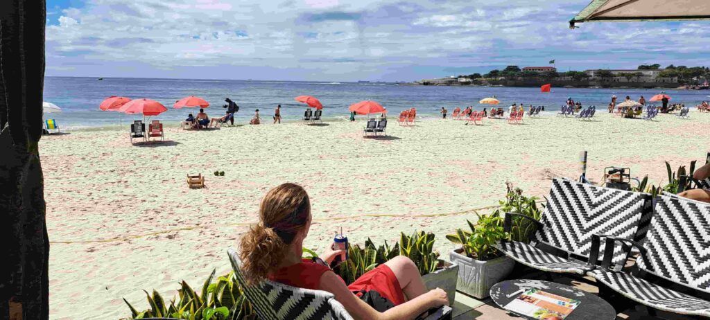 Mujer sentada en un chiringuito o quiosque de la playa de Copacabana, mirando hacia el Furete de Copacabana
