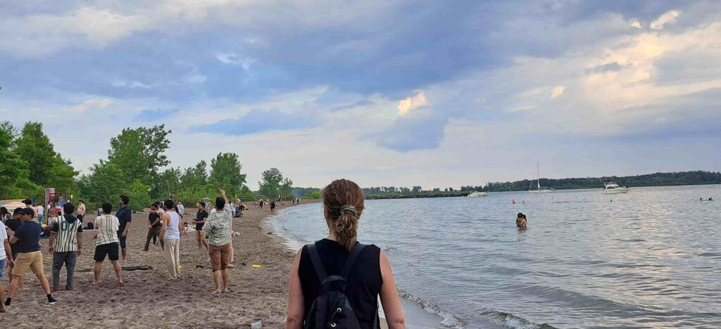 Mujer de espaldas viendo a la gente jugar en una playa de Ward´s Island en  Toronto, Canadá