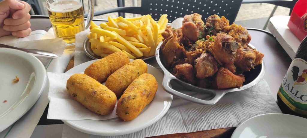 Mesa de un restaurante en Copacabana con  cervezas y tres platos con comida: pollo frito, coxinhas y patatas fritas