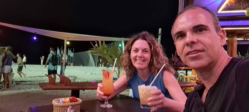 Hombre y mujer sonriendo, con cócteles en la mano, sentadas por la noche en una mesa de un chiringuito de la playa de Copacabana, en Río de Janeiro