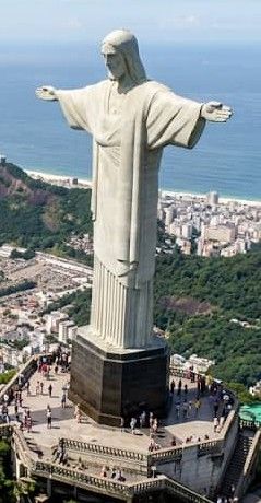 Cristo Redentor del Cerro Corcovado con gente a sus pies, que muestra la grandiosidad de la imagen en comparación con las personas, que se ven diminutas