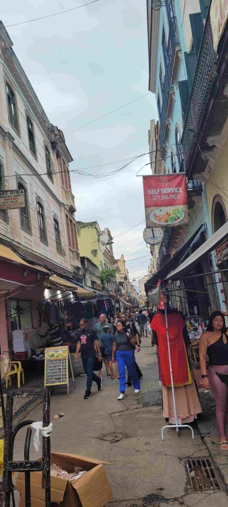 Calle estrecha del centro de Río de Janeiro con gente paseando y con comercios y restaurantes