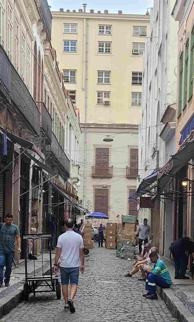 Hombre de espaldas en una calle del centro de Río de Janeiro con gente trabajando y algunas personas sentadas en la acera
