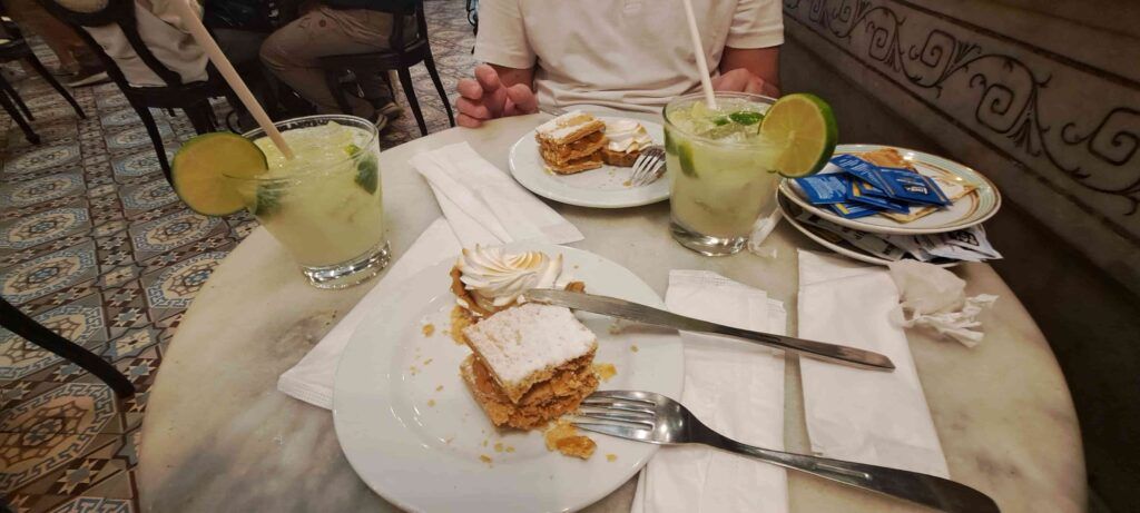 Mesa de la Confitería Colombo, en Río de Janeiro en la que ha y dos vasos con caipiriña y dos platos con pasteles