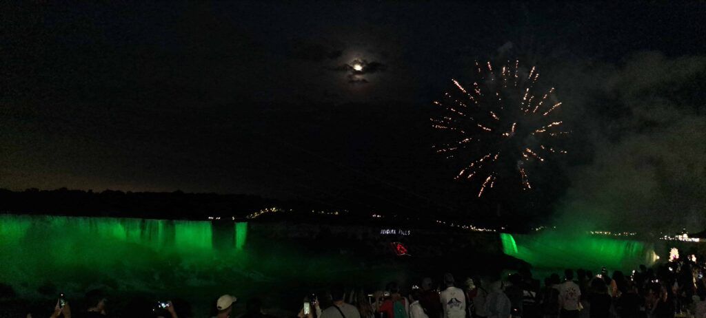 Fuegos artificiales sobre las Cataratas del Niágara iluminadas en verde, en una noche de verano