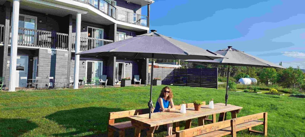 Mujer sentada en un banco de madera en el jardín del Motel Horizon, en Saint-Siméon, Canadá