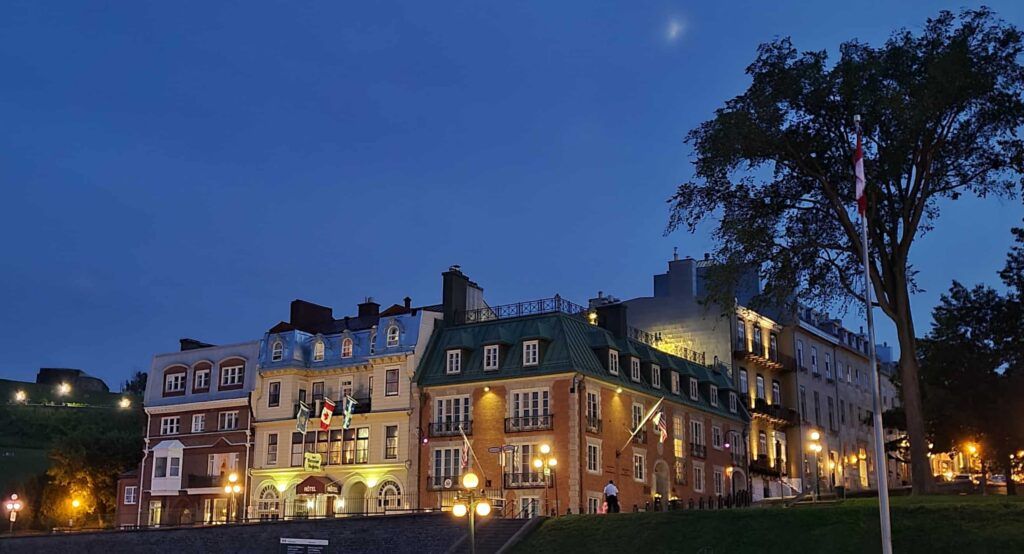 Casas iluminadas al anochecer junto al Hotel Fairmont Chateau Le Frontenac en Quebec, Canadá