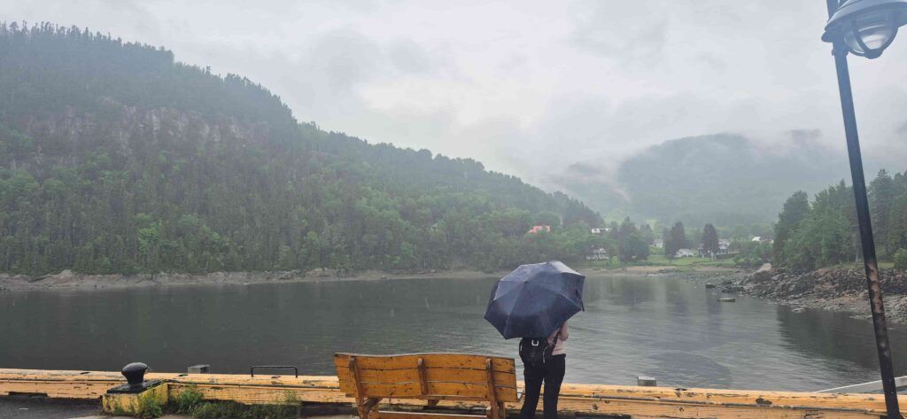 Mujer de espaldas con paraguas, contemplando el Fiordo del Saguenay, desde Sainte-Rose-du-Nord en Quebec, Canadá