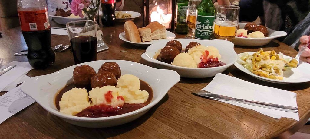 plato de Köttbullar tradicionales (las famosas albóndigas suecas caseras) servidas con un suavísimo puré de patata, salsa gravy, pepinillos y arándanos rojos